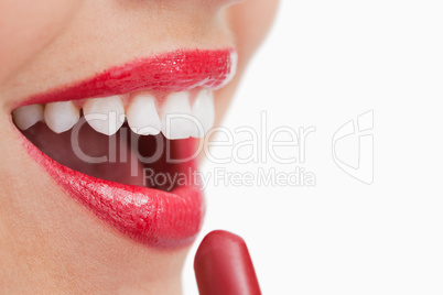 Happy woman putting lipstick on her lips