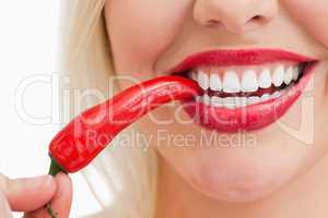 Happy woman eating a red chili