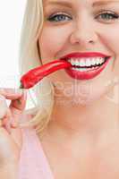 Cheerful blonde woman eating a chili