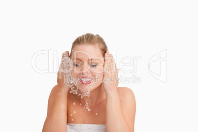 Smiling blonde woman splashing her face