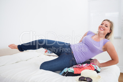 Smiling woman trying to close her suitcase