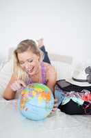 Student with a suitcase pointing on a globe