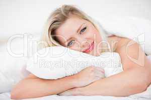 Blonde smiling while embracing a pillow