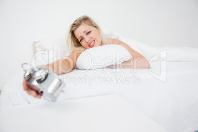 Upset blonde looking at her alarm clock