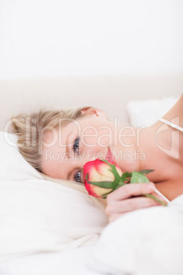 Blue eyed woman smelling a rose