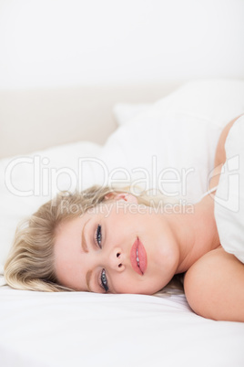 Pretty woman lying under a white duvet