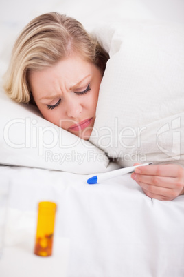 Sick woman looking at her thermometer