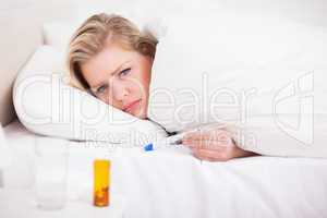 Sick blonde woman with a thermometer