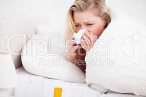 Blonde woman sneezing