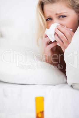 Sad blonde woman sneezing