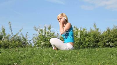 Woman seated on lawn talking on her mobile