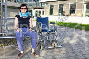 Woman sitting on bench next to the wheelchair