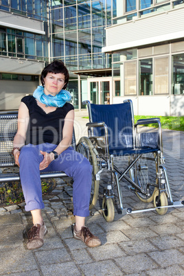 Woman sitting on bench next to the wheelchair