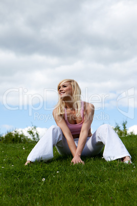 Happy woman sitting on grassy slope