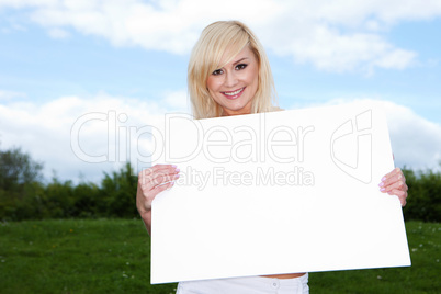 Blonde woman holding empty sign outside