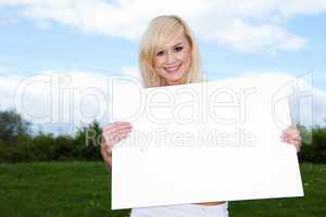 Blonde woman holding empty sign outside