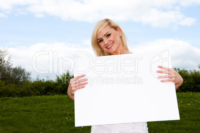 Blonde woman holding empty sign outside