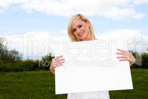 Blonde woman holding empty sign outside