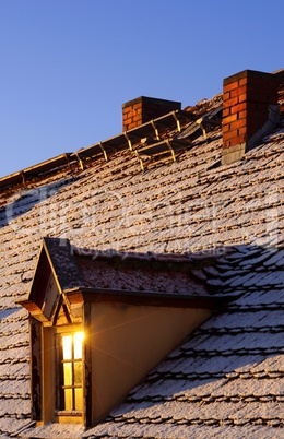 Dach eines Hauses mit Erker und Schornstein im Winter bei Schnee
