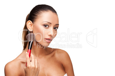 Young beautiful woman using brush to apply makeup