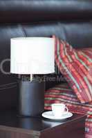 bed with a pillow, a cup of tea on the bedside table and lamp
