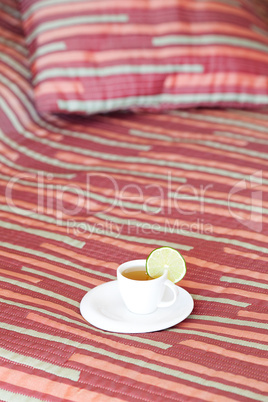 bed with two pillows, a cup of tea on the blanket