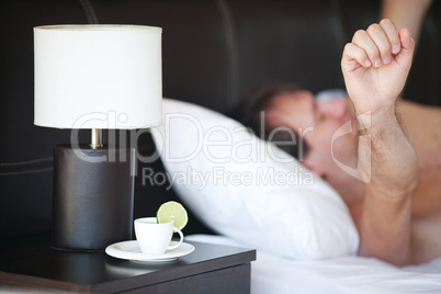 waking up man and a cup of tea on the bedside table and lamp