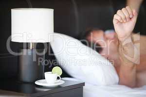 waking up man and a cup of tea on the bedside table and lamp