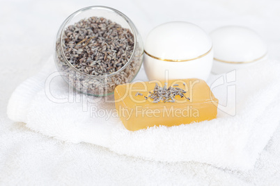 cosmetic containers, soap and lavender on a white towel