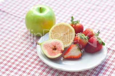 apple, lemon, fig and strawberries on a plate