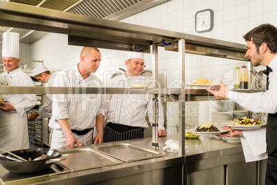 Restaurant waiter take meal from professional cook