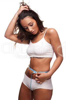 Beautiful tanned woman measuring her waist