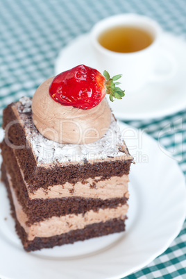 beautiful cake with strawberry and tea on plaid fabric