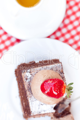 beautiful cake with strawberry and tea on plaid fabric