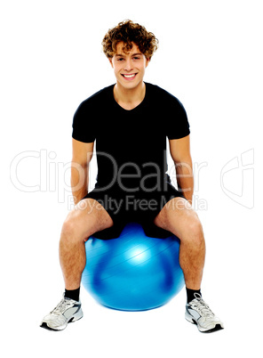 Handsome guy seated on exercise ball