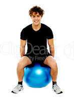 Handsome guy seated on exercise ball