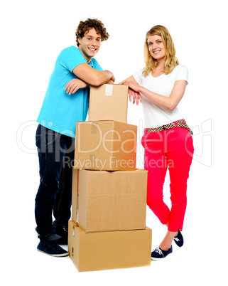 Teenager couple posing beside cardboard boxes