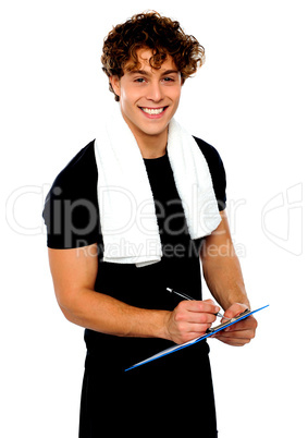 Smiling male trainer writing on clipboard