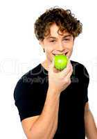 Young man eating fresh healthy green apple