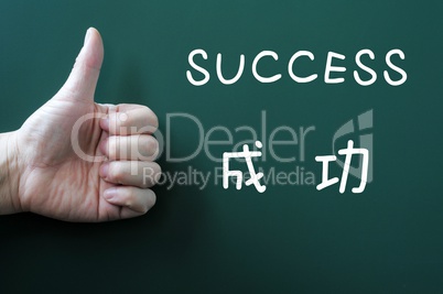 Success written on a blackboard with a thumb up