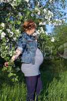 Pregnant woman standing apple tree