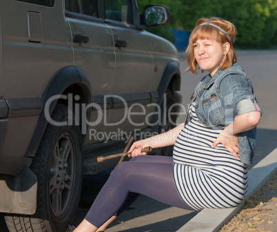 Pregnant Woman with a Wheel Brace near Car