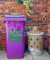 Wheelie bin and garden incinerator against brick wall