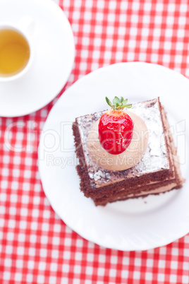 beautiful cake with strawberry and tea on plaid fabric