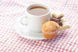 bar of chocolate,tea and muffin on plaid fabric