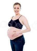 Smiling pregnant woman caressing her belly