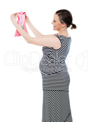 Pregnant woman looking at baby cloth, rejoicing