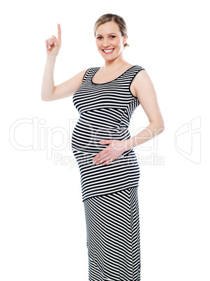 Pregnant woman pointing up at copyspace