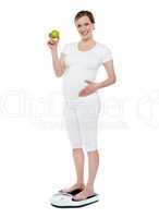 Pregnant woman standing on weighing machine