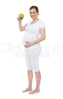 Pregnant woman showing fresh green apple